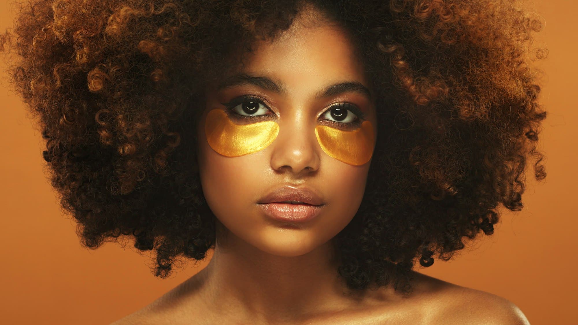 Young beautiful african woman wearing golden eye patches against dark circles